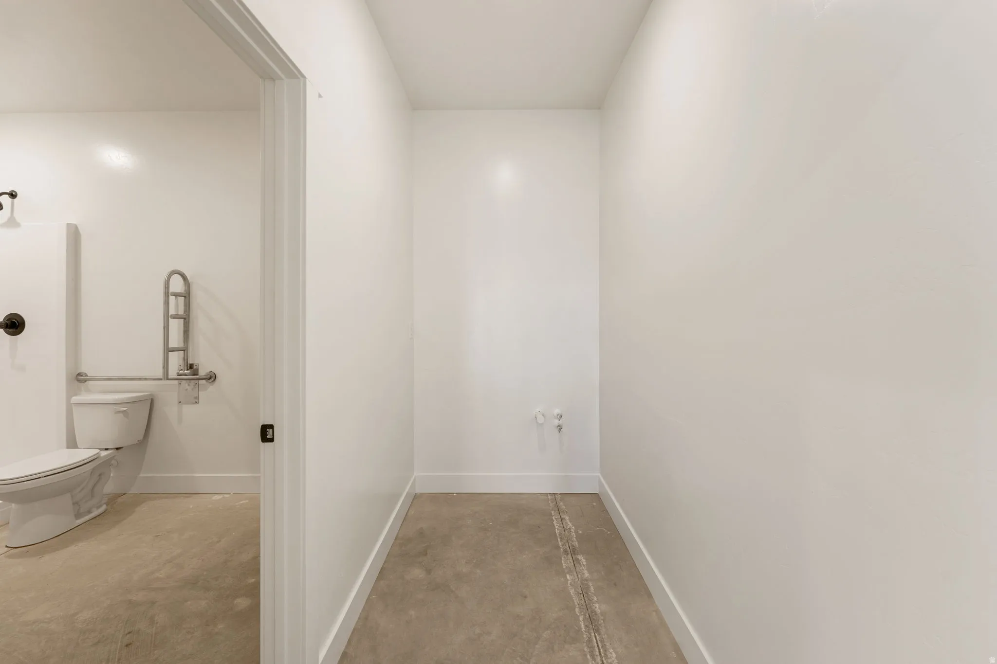 Corridor featuring concrete floors and baseboards