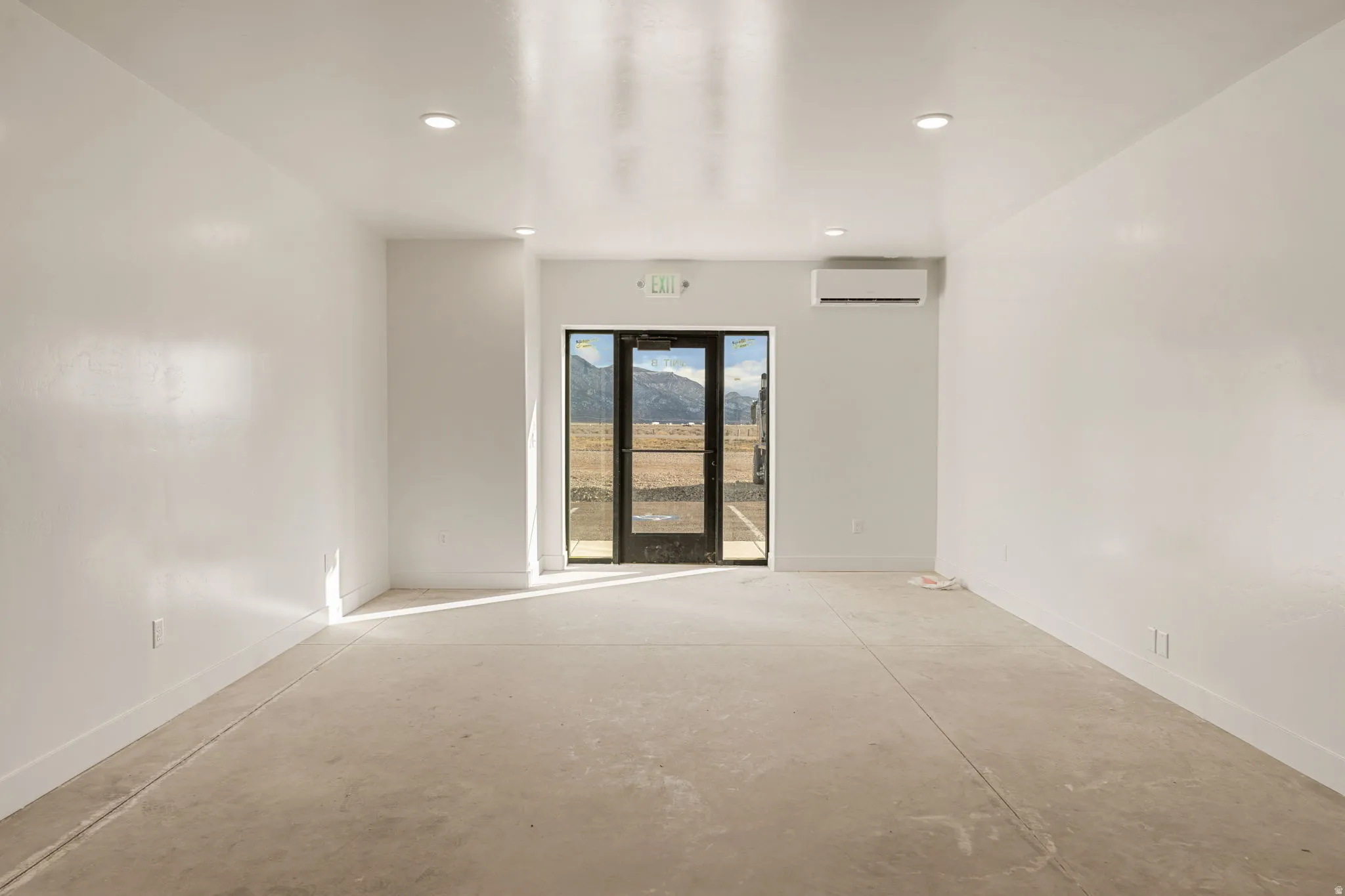 Empty room with unfinished concrete flooring and recessed lighting