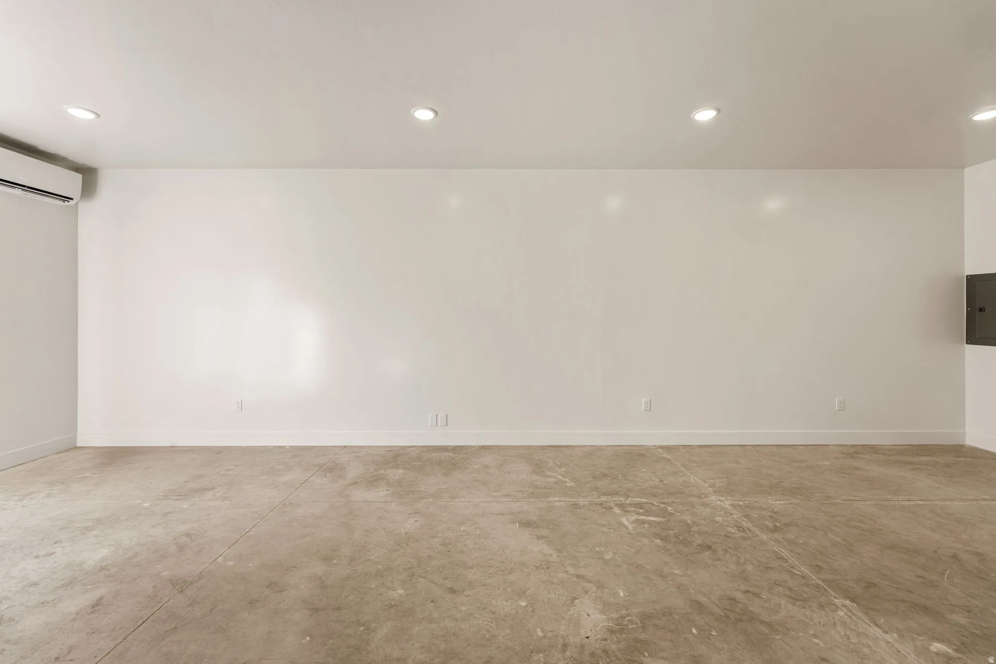 Unfurnished room featuring concrete flooring, recessed lighting, and electric panel