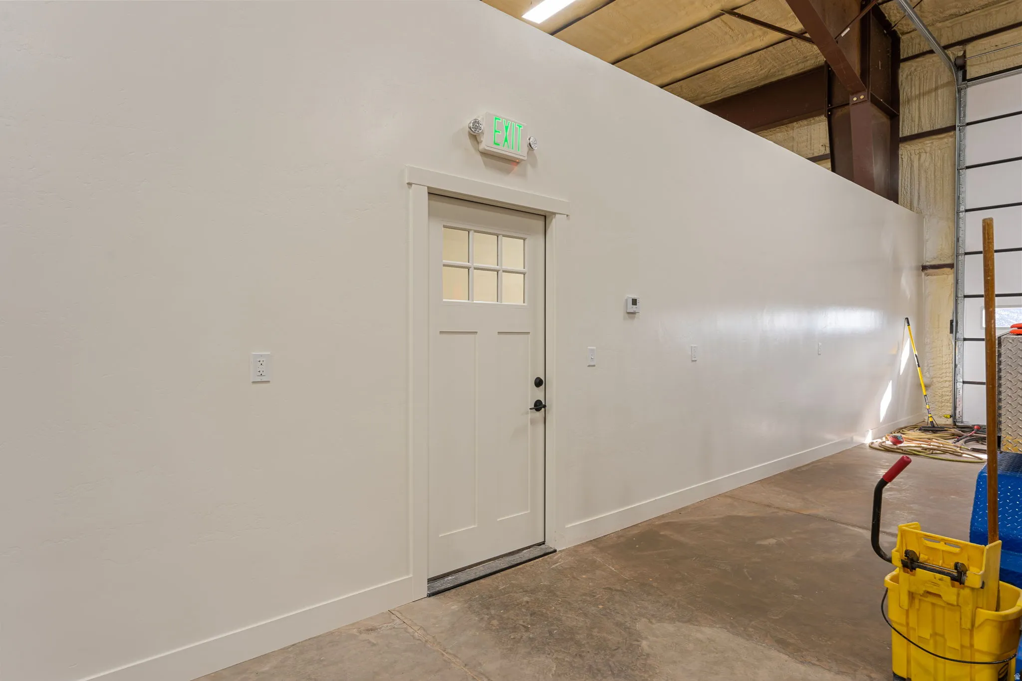Foyer entrance featuring unfinished concrete flooring and a high ceiling