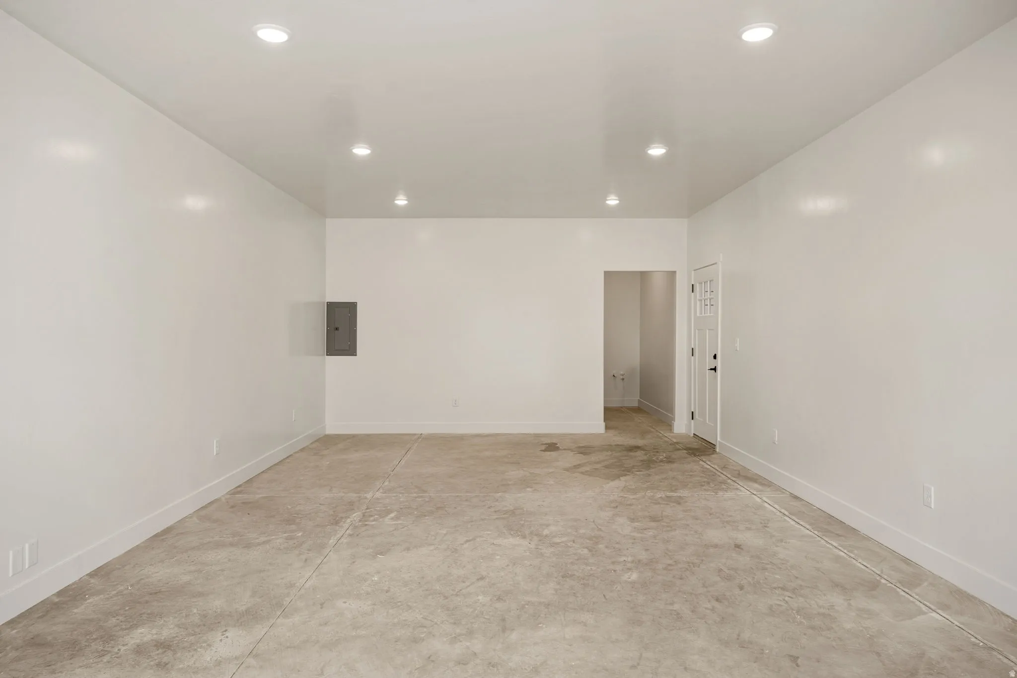 Unfurnished room with concrete floors, electric panel, and recessed lighting