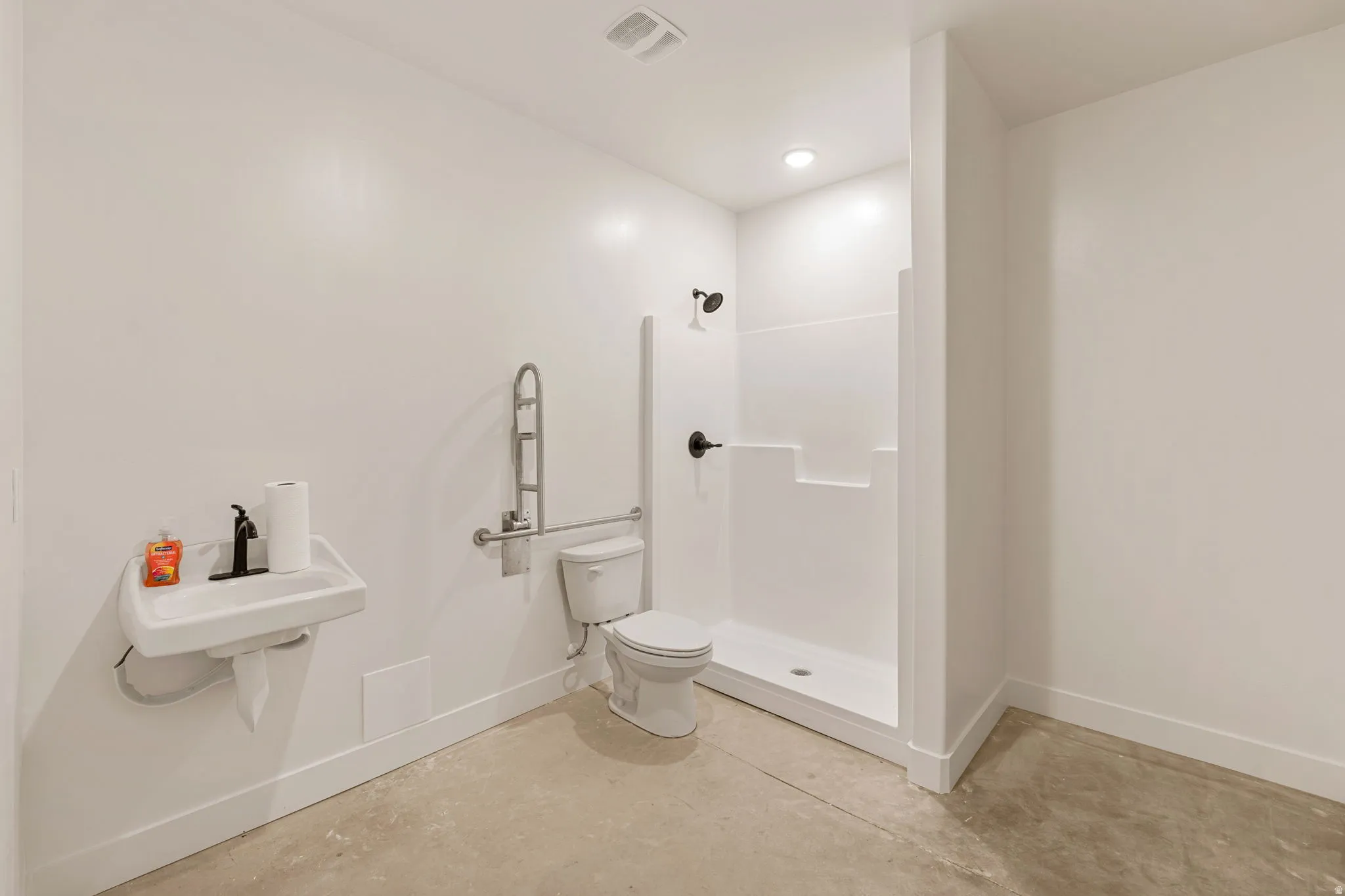 Full bathroom featuring concrete floors, a shower stall, and recessed lighting