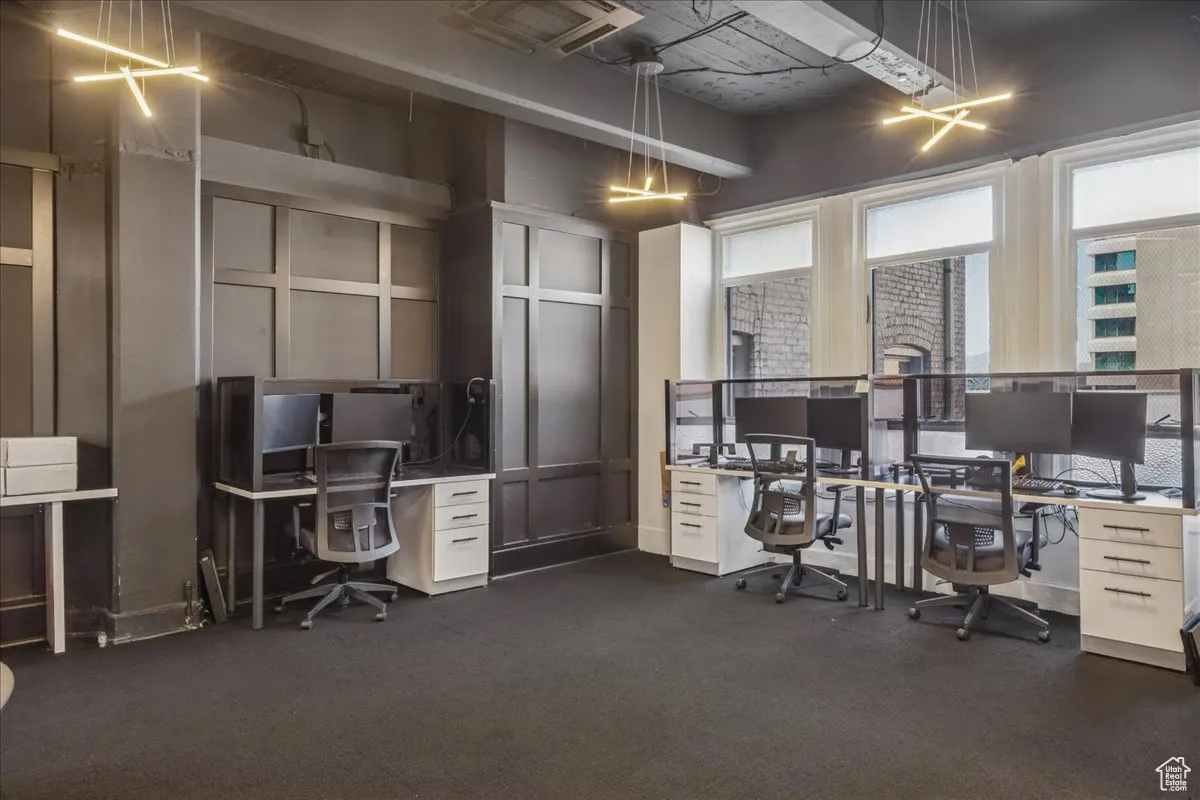 Office with dark carpet, paneled walls, and natural light