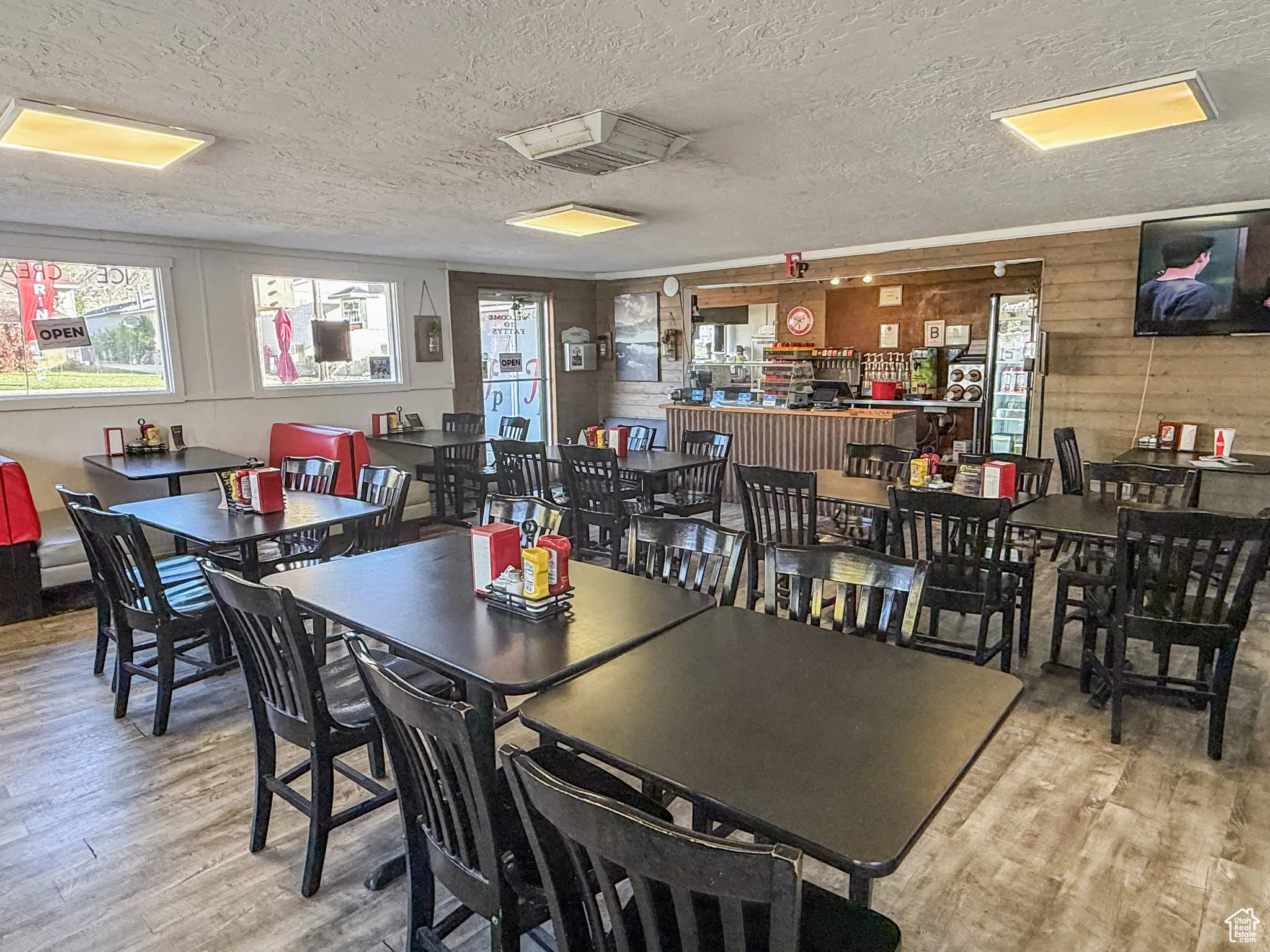 Dining area featuring a textured ceiling, wood walls, and light wood-style flooring