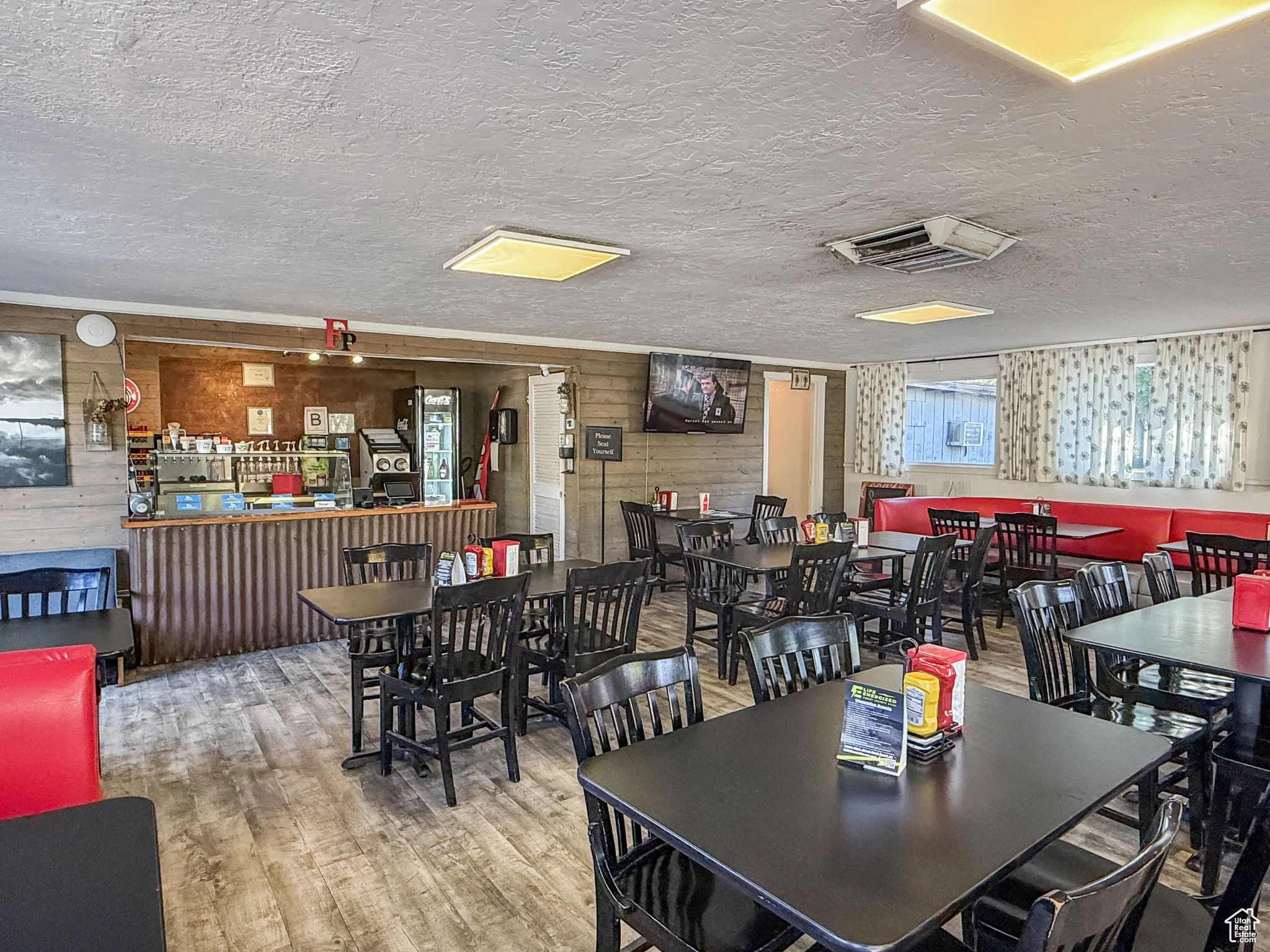 Dining space with wood walls, wood finished floors, and a textured ceiling