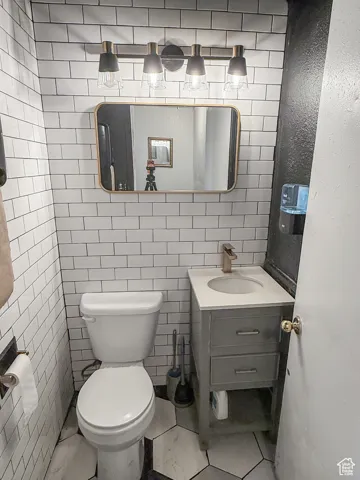 Half bath with vanity, tile walls, and tile patterned floors