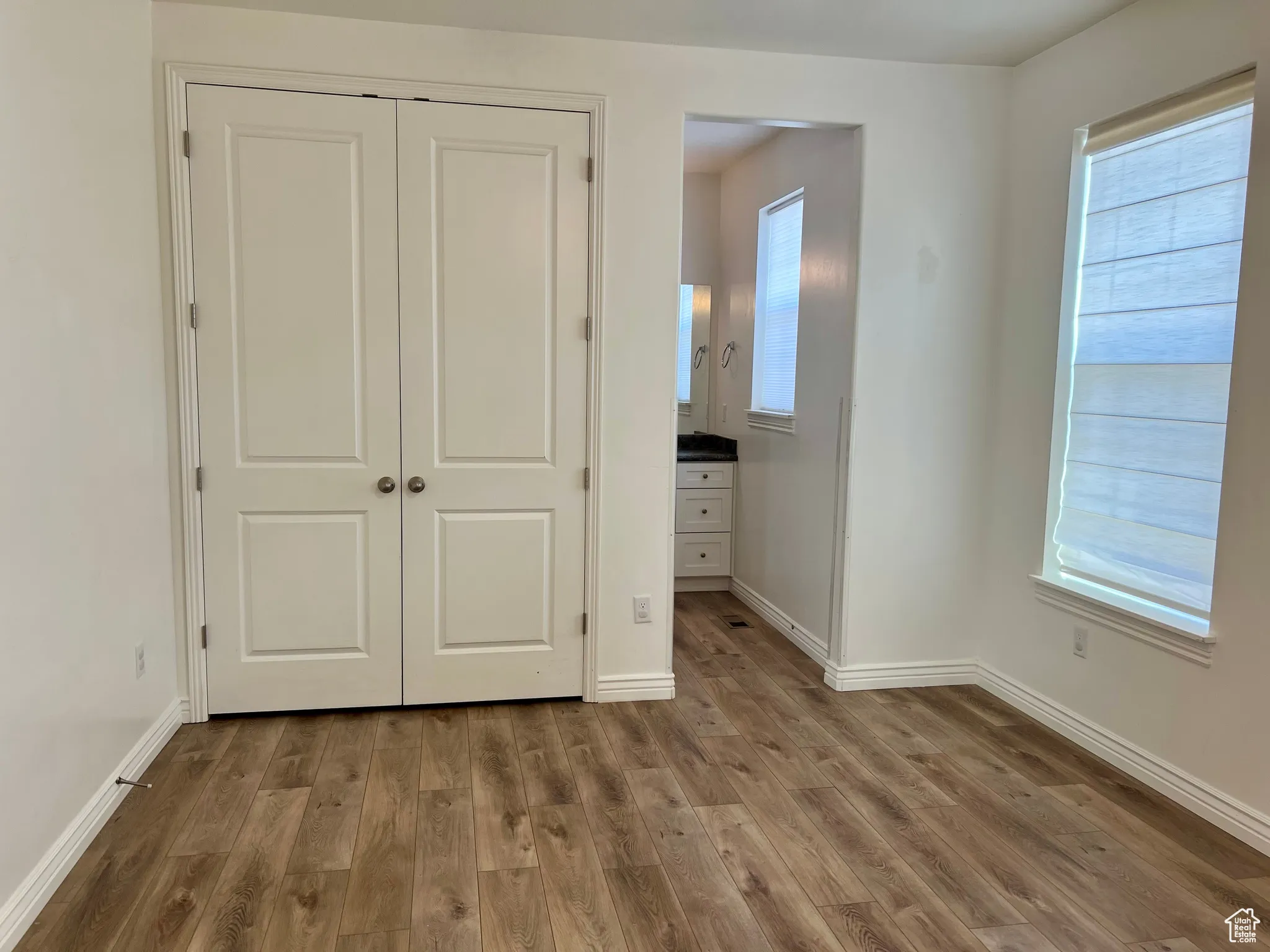 Unfurnished bedroom featuring ensuite bath, light wood-style floors, and a closet