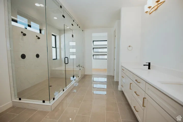Full bathroom featuring double vanity, a stall shower, light tile patterned floors, and recessed lighting
