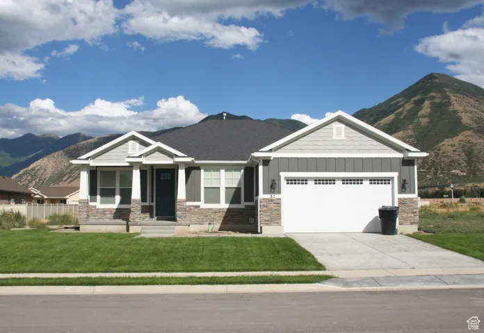 Craftsman inspired home featuring board and batten siding, a mountain view, stone siding, a front yard, and concrete driveway