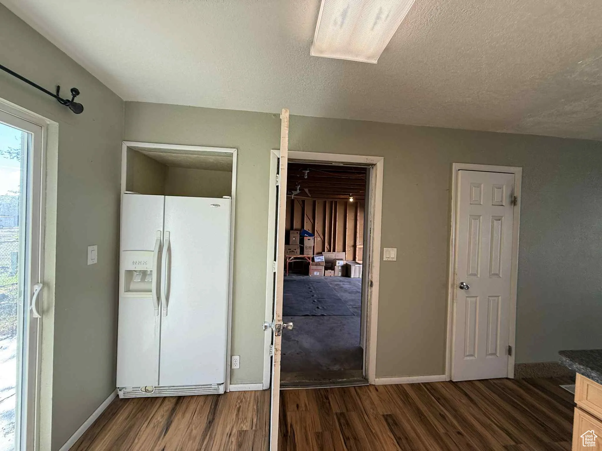 View of Kitchen featuring white refrigerator with ice dispenser, door into garage and pantry