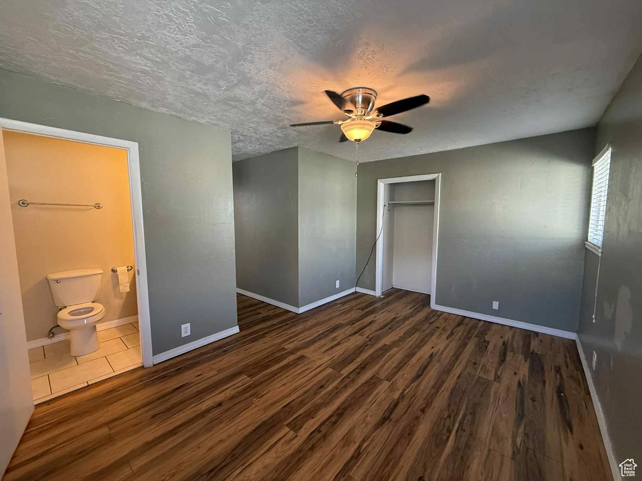 Master bedroom with dark wood-style flooring, ceiling fan, a textured ceiling, a closet, and master bathroom