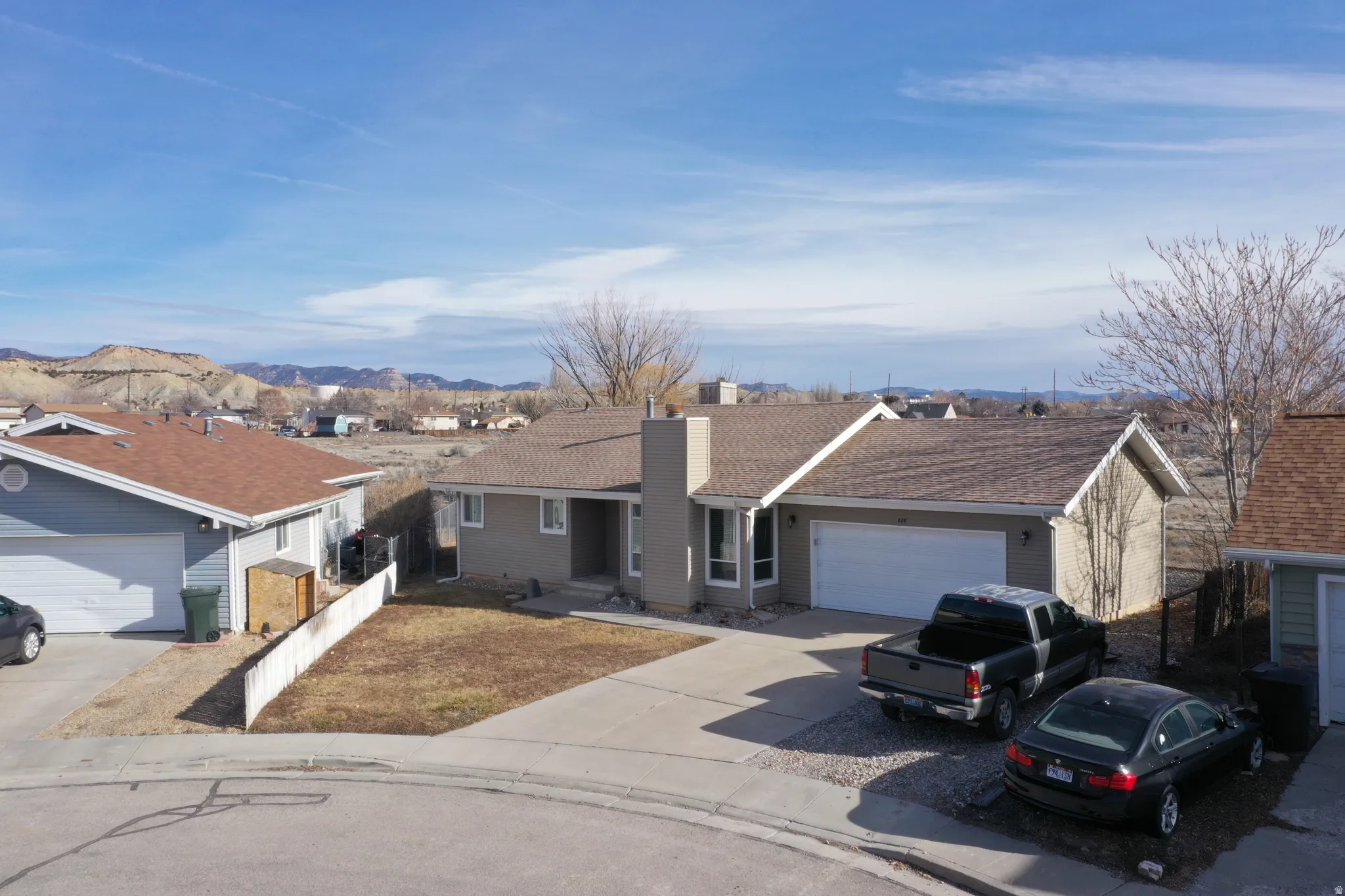 Single story home with concrete driveway, a chimney, a mountain view, an attached garage, and a residential view