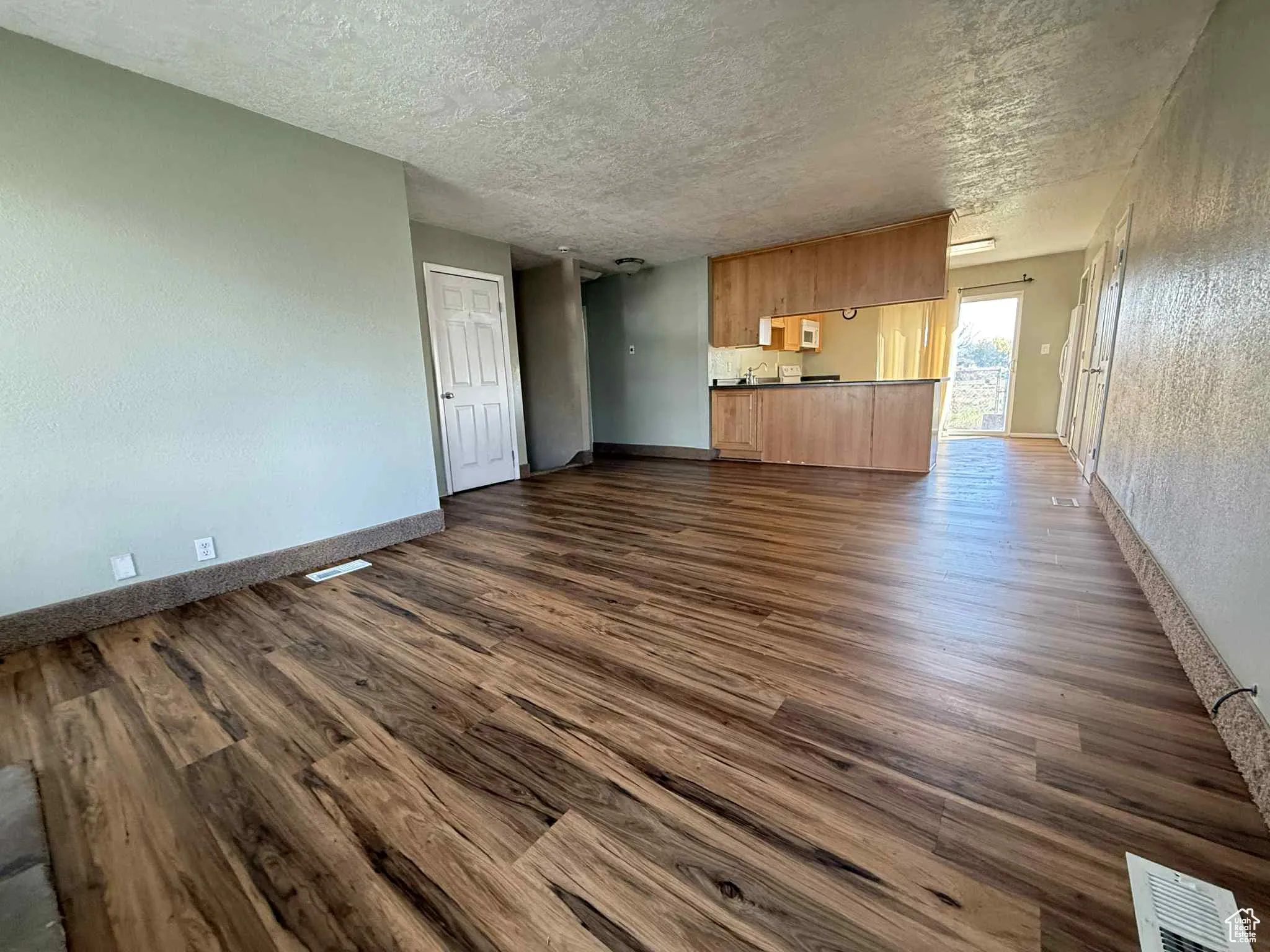 Living room with view into kitchen, coat closet, basement stairs and hallway to bedrooms