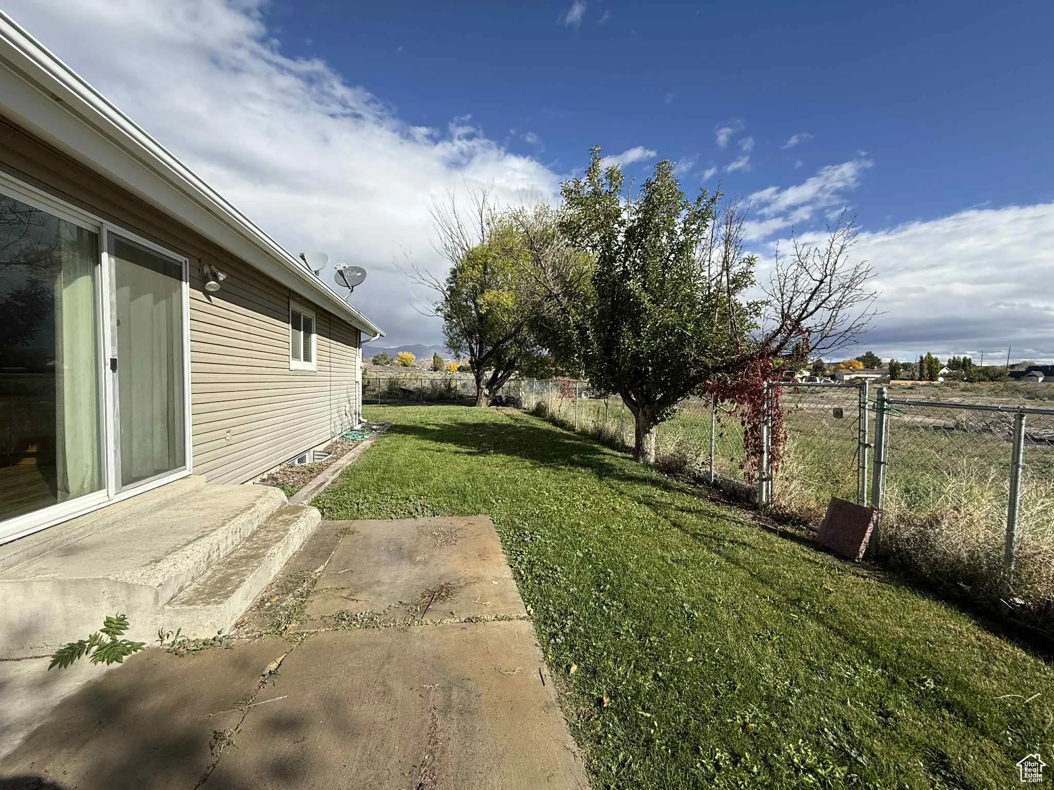 Fenced backyard featuring a patio area and fields behind home