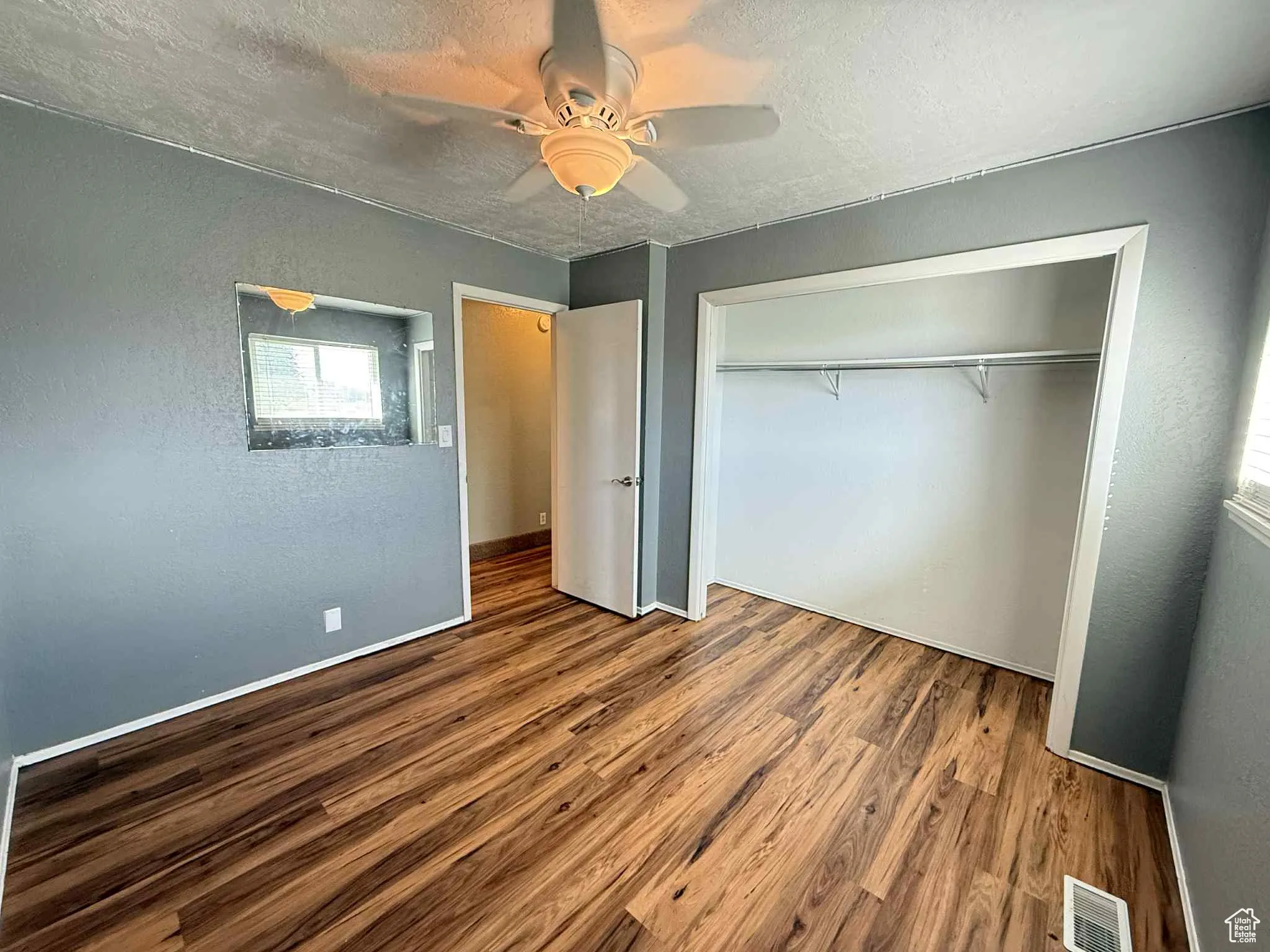 Bedroom 1 featuring wood finished floors, ceiling fan, a textured ceiling, and a closet