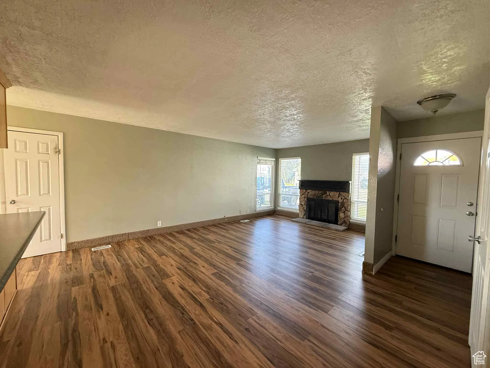 Opposite living room view featuring gas fireplace and hall to the front door