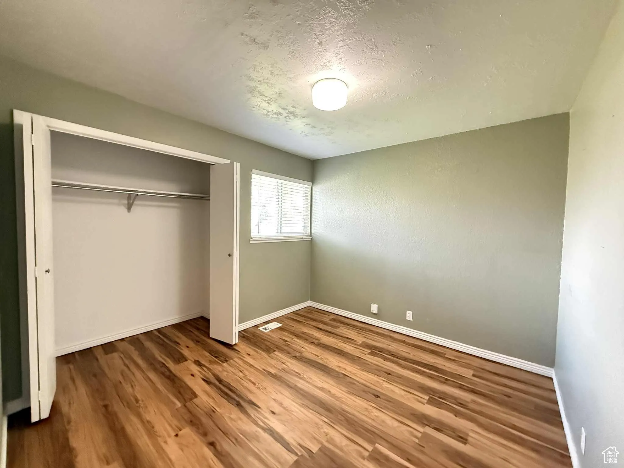Bedroom 2 featuring a textured ceiling, wood finished floors, and a closet