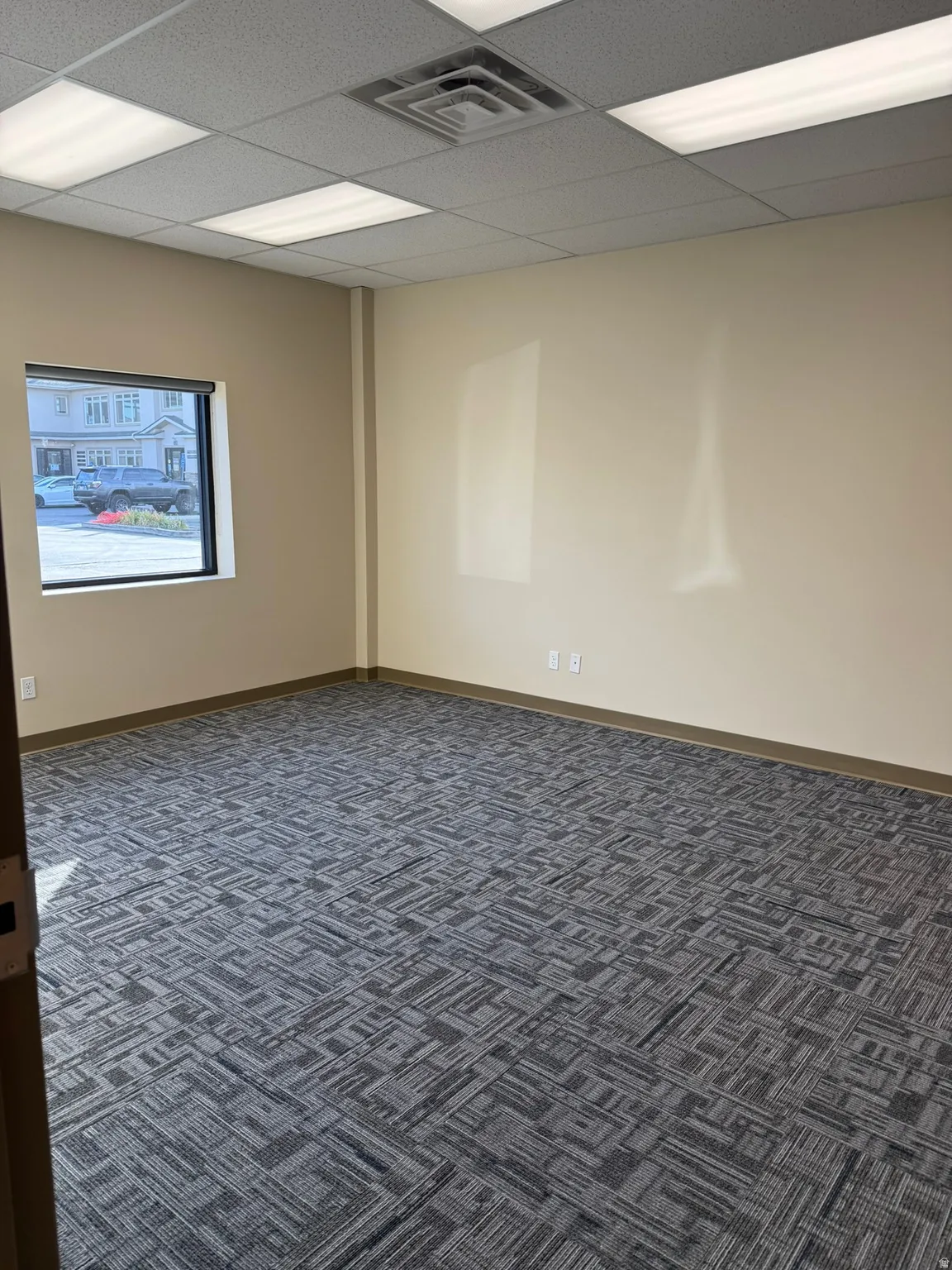 Empty room with dark carpet and a drop ceiling