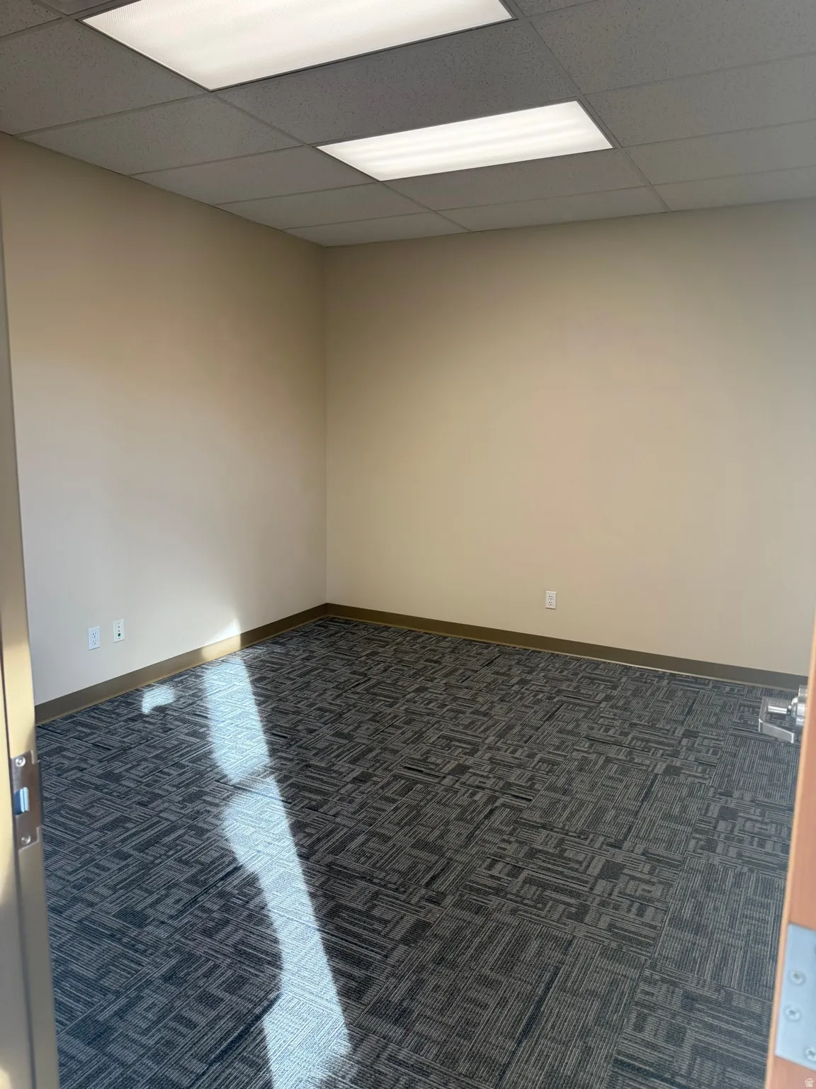 Carpeted spare room featuring a paneled ceiling and baseboards