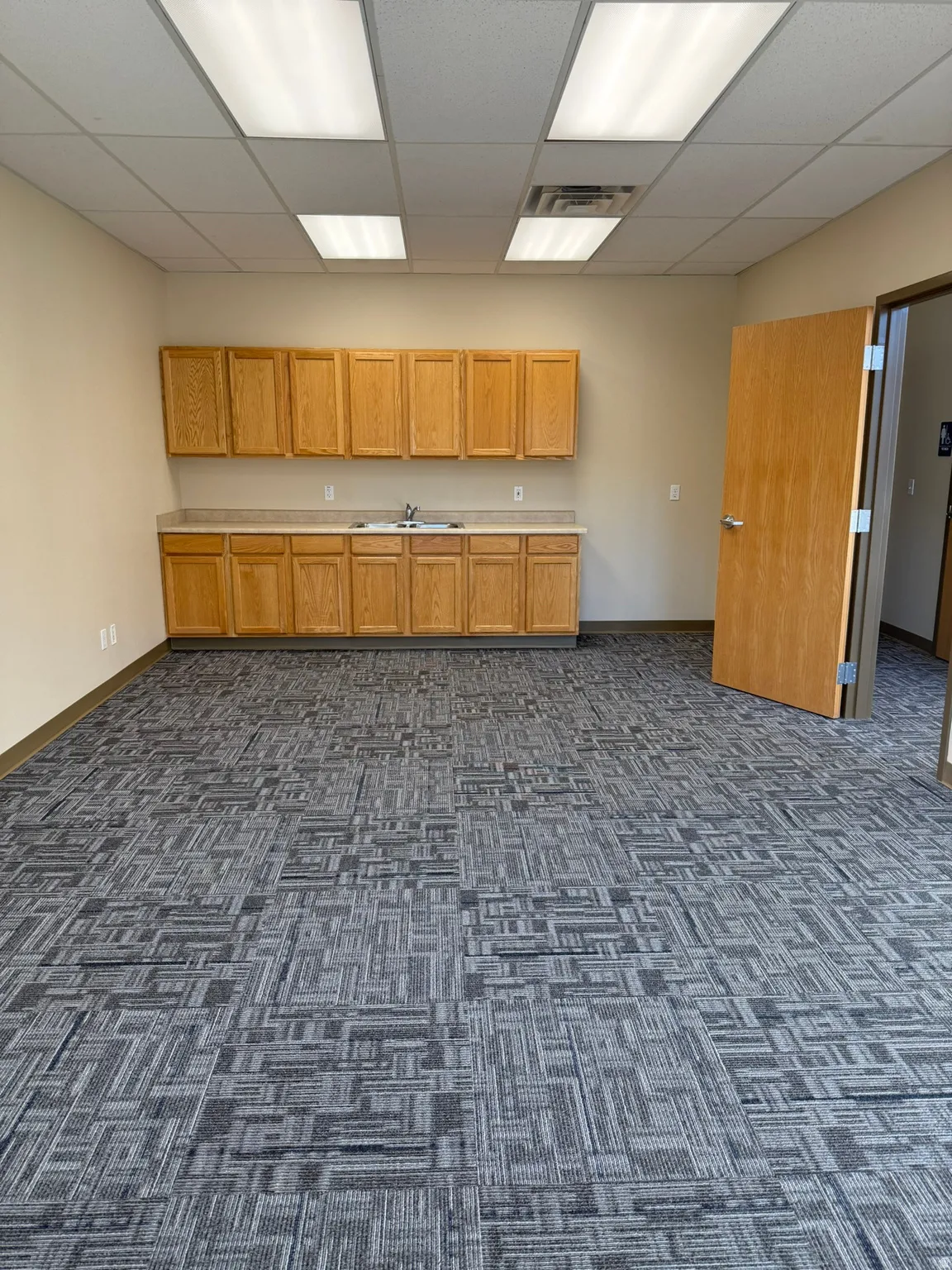 Kitchen featuring a drop ceiling, light countertops, and dark colored carpet