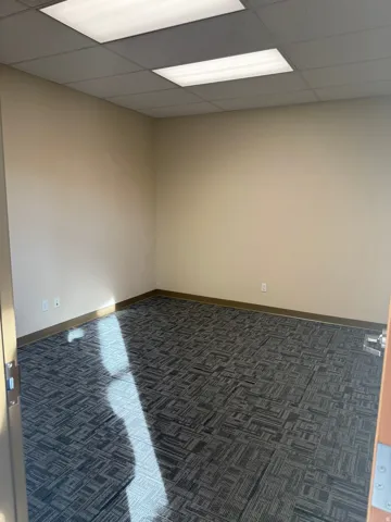 Carpeted spare room featuring a paneled ceiling and baseboards