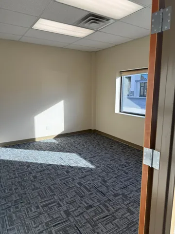 Empty room featuring dark colored carpet and a drop ceiling