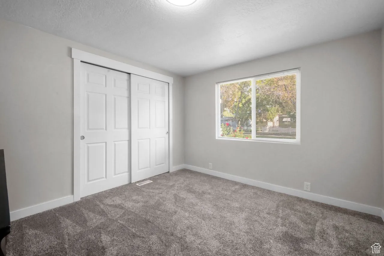 Unfurnished bedroom with carpet, a textured ceiling, and a closet
