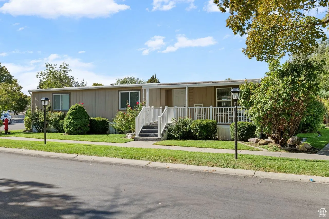Manufactured / mobile home with covered porch and a front lawn