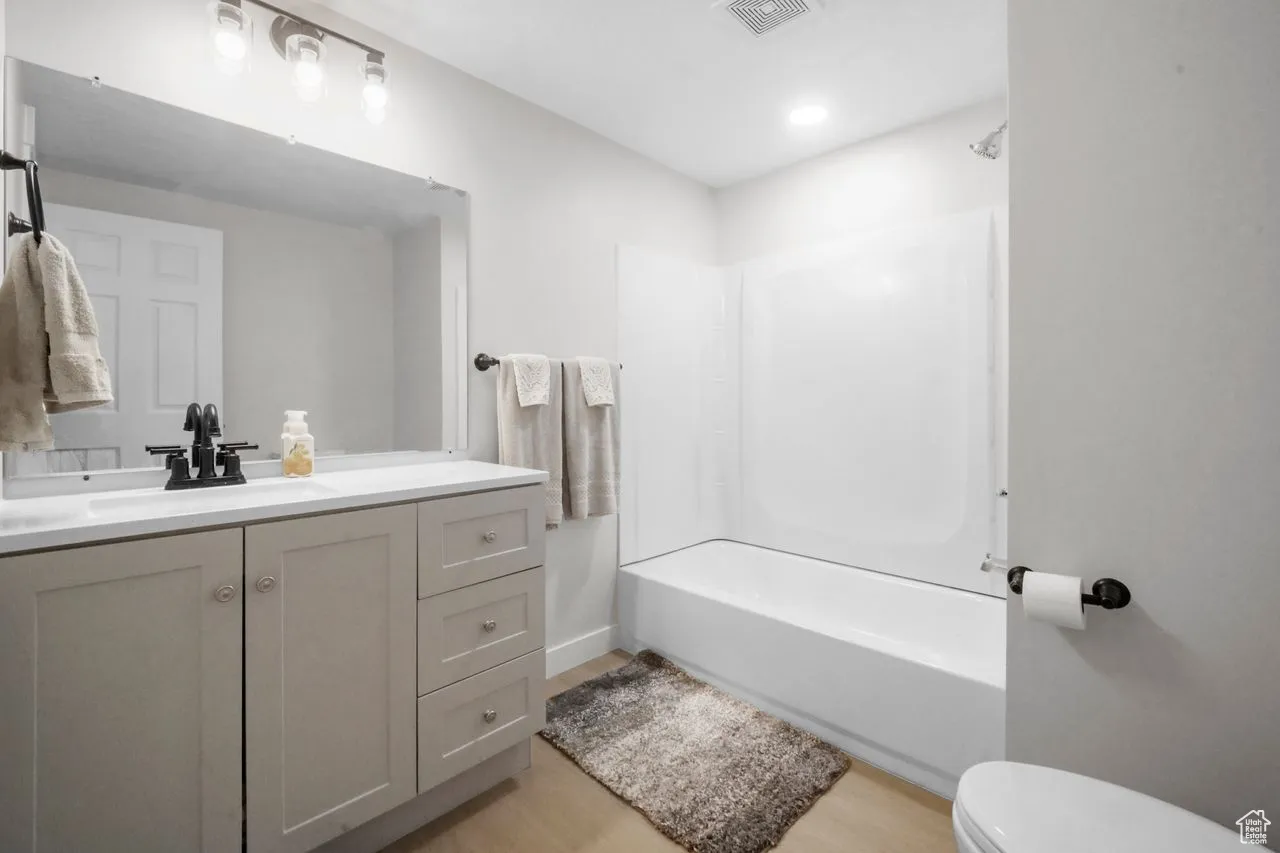 Full bathroom featuring bathtub / shower combination, vanity, and light wood-style flooring