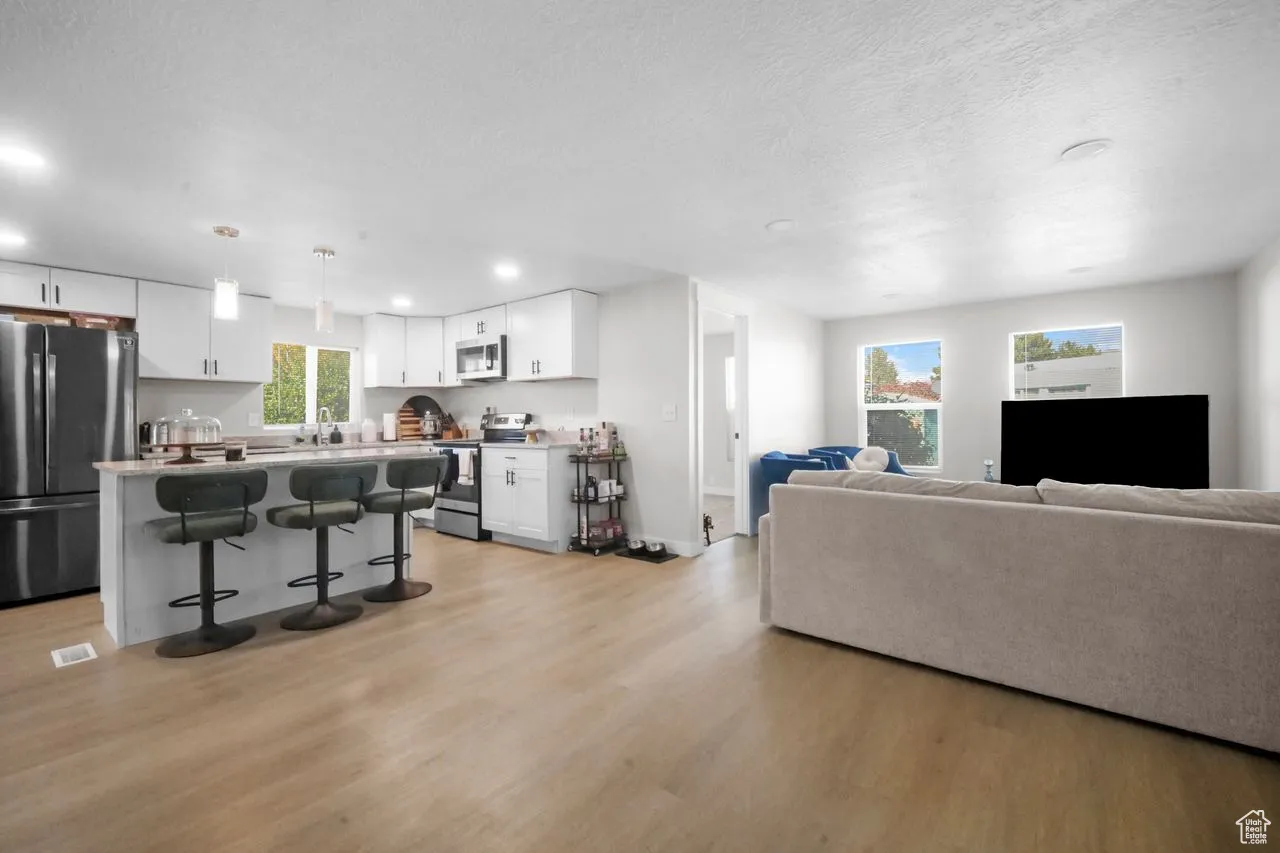 Living room featuring light wood-style flooring, a textured ceiling, and recessed lighting