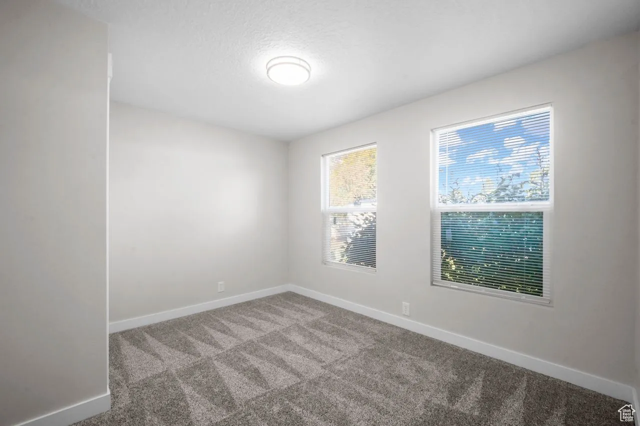 Carpeted spare room featuring baseboards and a textured ceiling