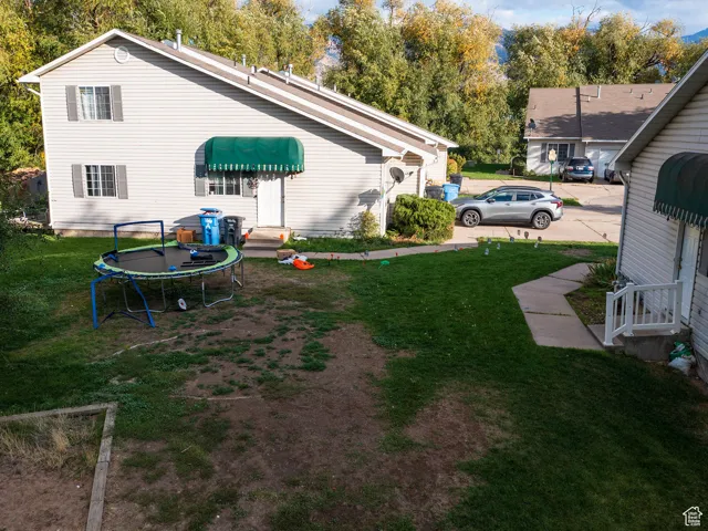 View of green lawn with a trampoline and view of scattered trees