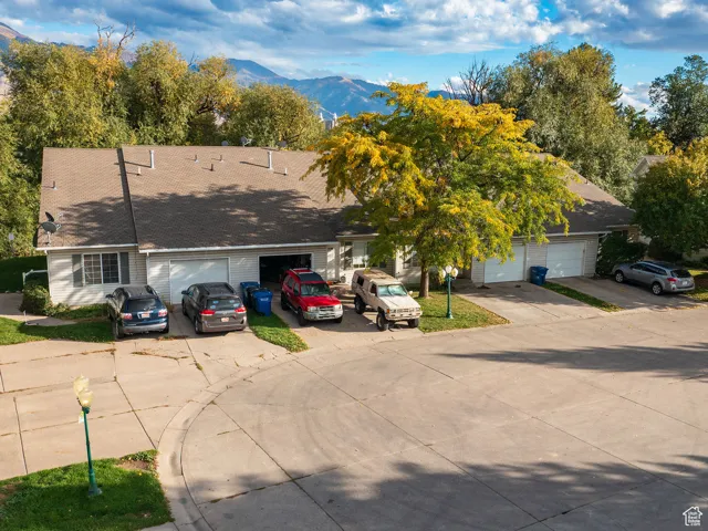 View of front facade with a mountain view, driveway, and roof with shingles