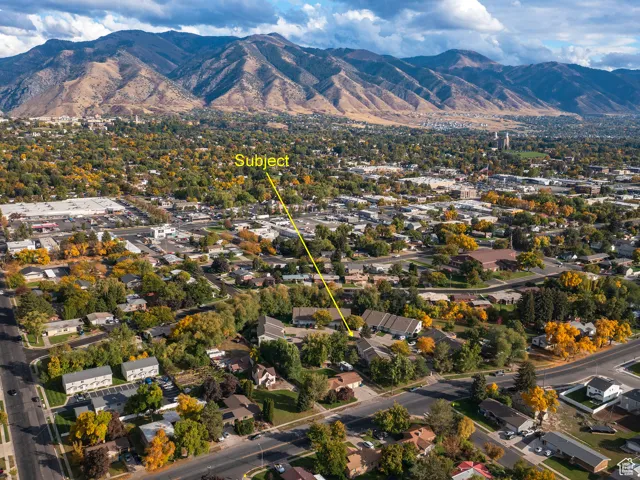 Aerial view of property and surrounding area with a mountainous background and a tree filled landscape