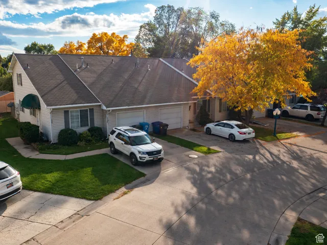 View of front facade with driveway, a front yard, roof with shingles, and an attached garage