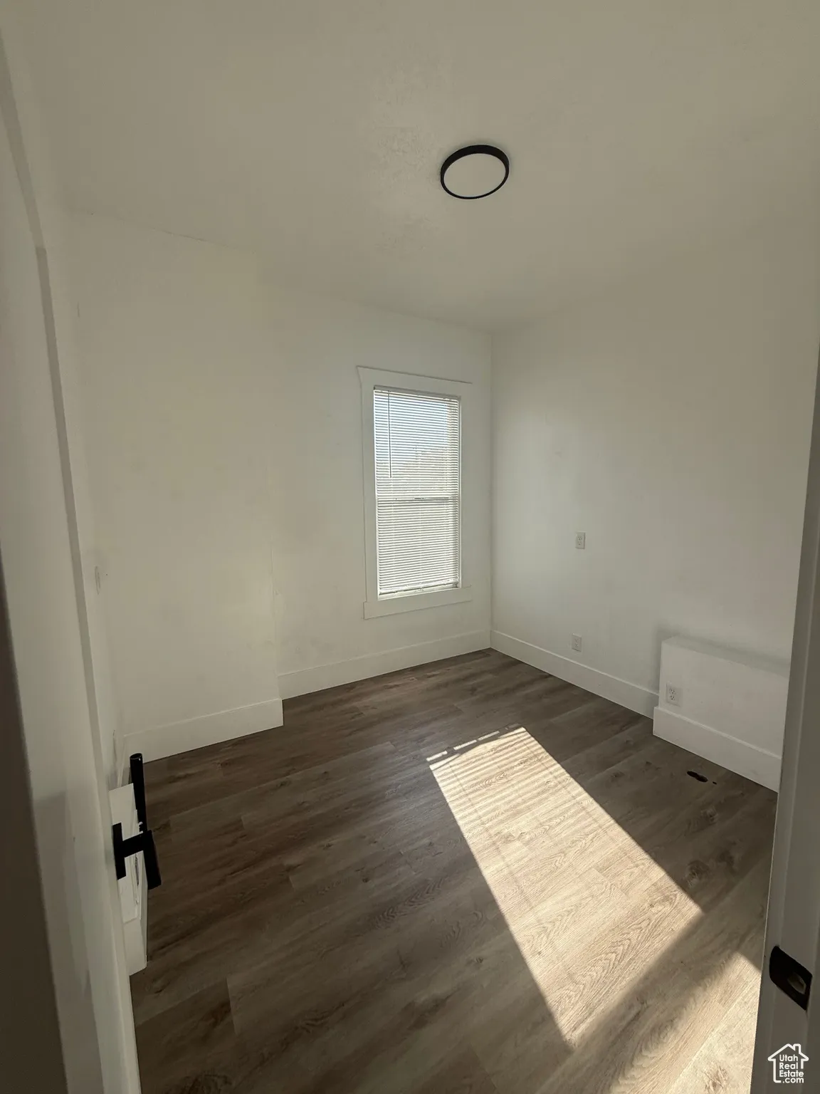 Room with dark wood-style flooring and baseboards