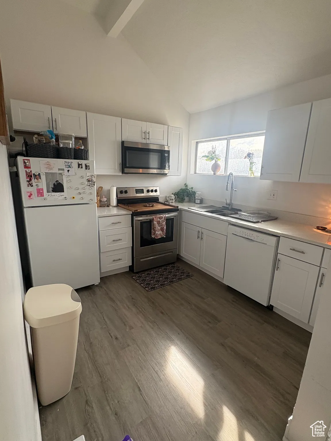 Kitchen with white cabinetry, light countertops, stainless steel appliances, and dark wood finished floors