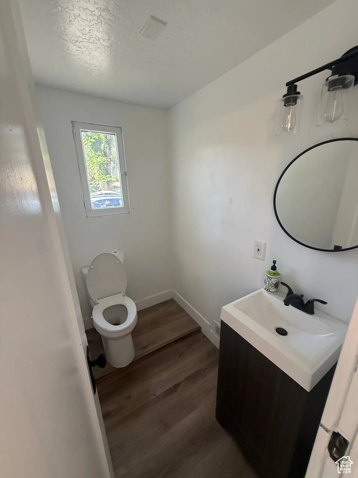 Half bath with vanity, dark wood finished floors, and a textured ceiling