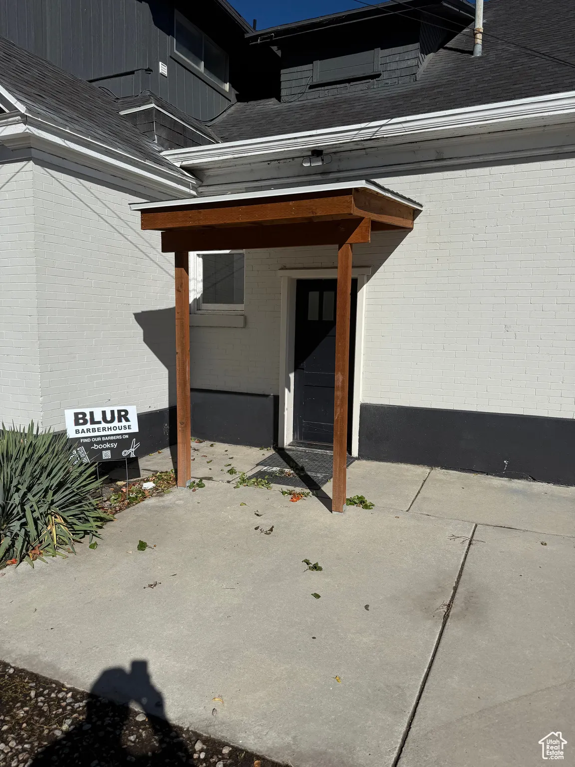 Doorway to property with roof with shingles and brick siding