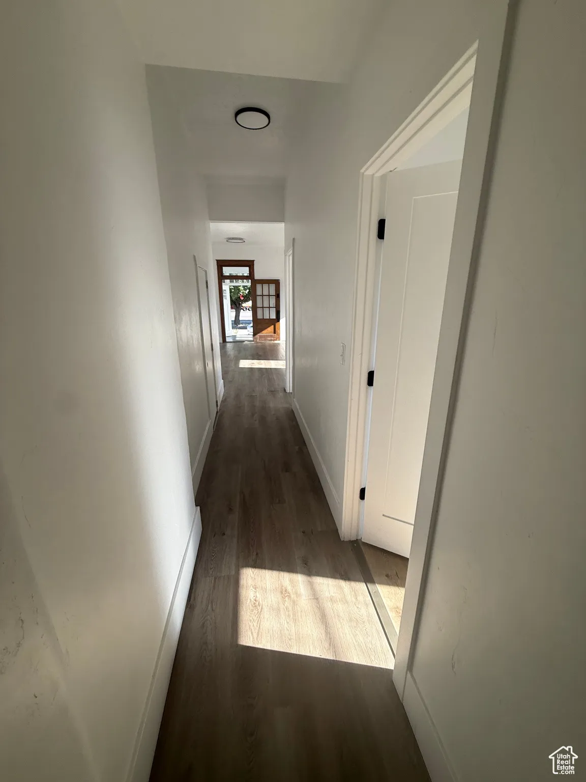 Corridor with dark wood-type flooring and baseboards