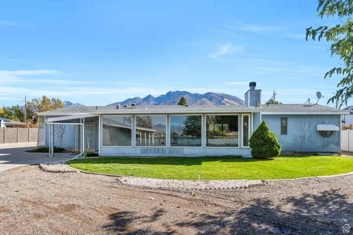 Rear view of property featuring a mountain view, a chimney, a sunroom, and a shingled roof