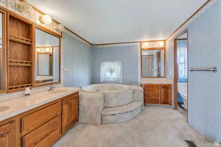 Bathroom featuring a garden tub, double vanity, and ornamental molding