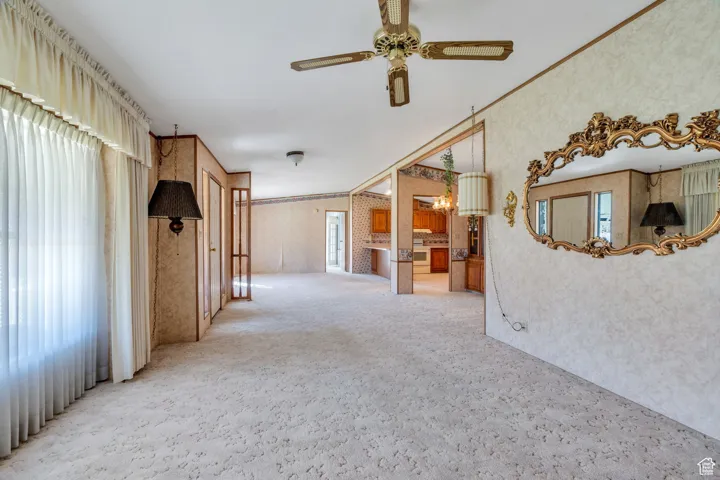 Spare room with crown molding, carpet floors, ceiling fan, and wallpapered walls