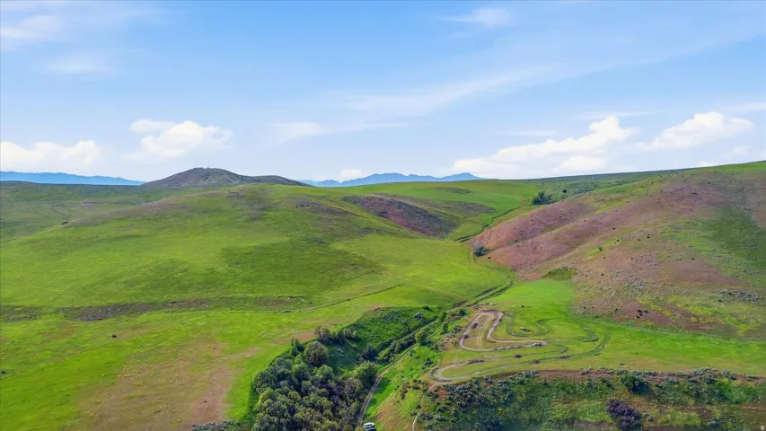Expansive rolling hills featuring verdant grasslands and distant mountains