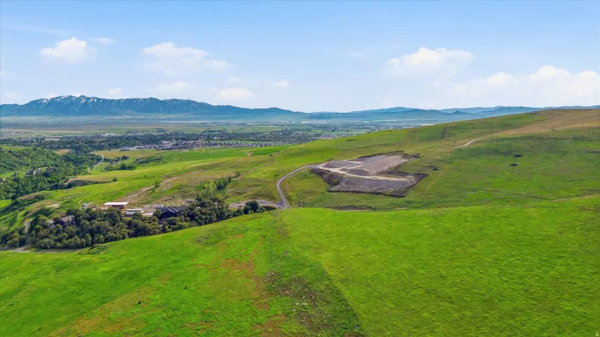 Expansive green hillside property with distant mountain range backdrop