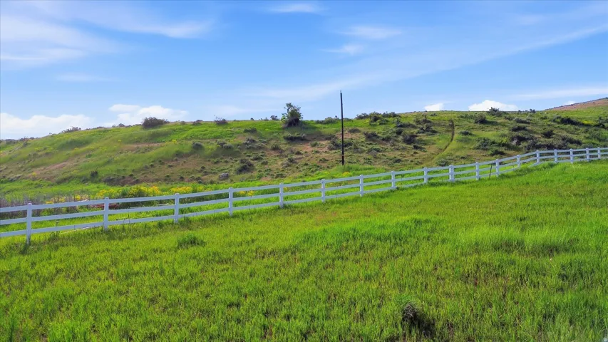 Expansive green acreage with a white post-and-rail fence