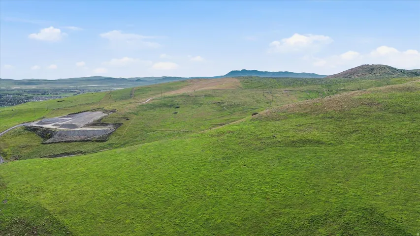 Expansive green hills with a distant city outline