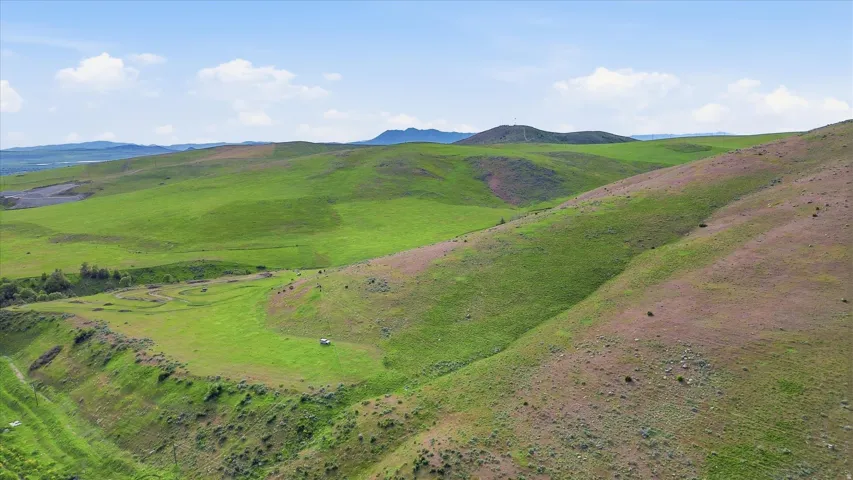 Expansive rolling hills with vibrant green and muted brown grasses