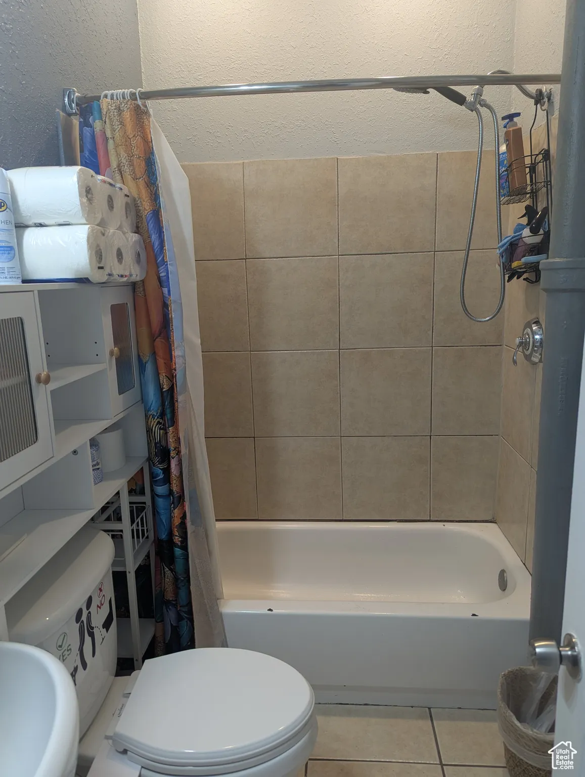 Full bath featuring shower / bathtub combination with curtain, tile patterned flooring, and a textured wall