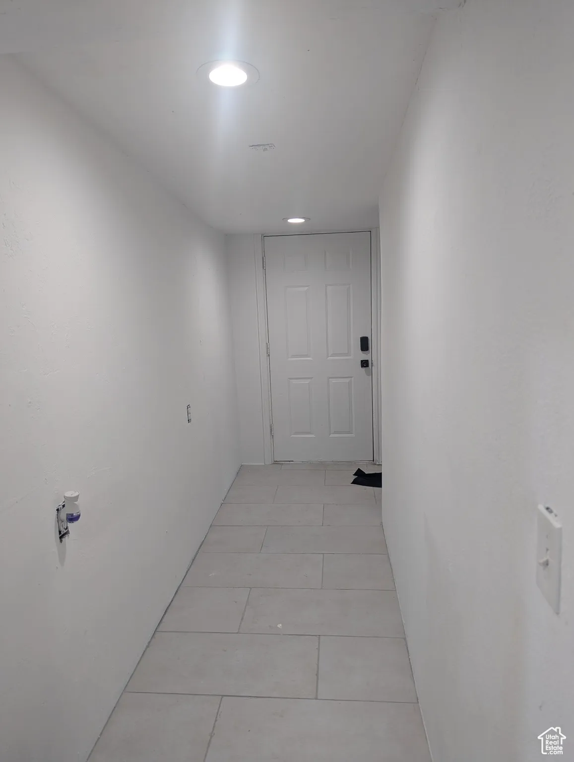 Hall with light tile patterned floors and recessed lighting